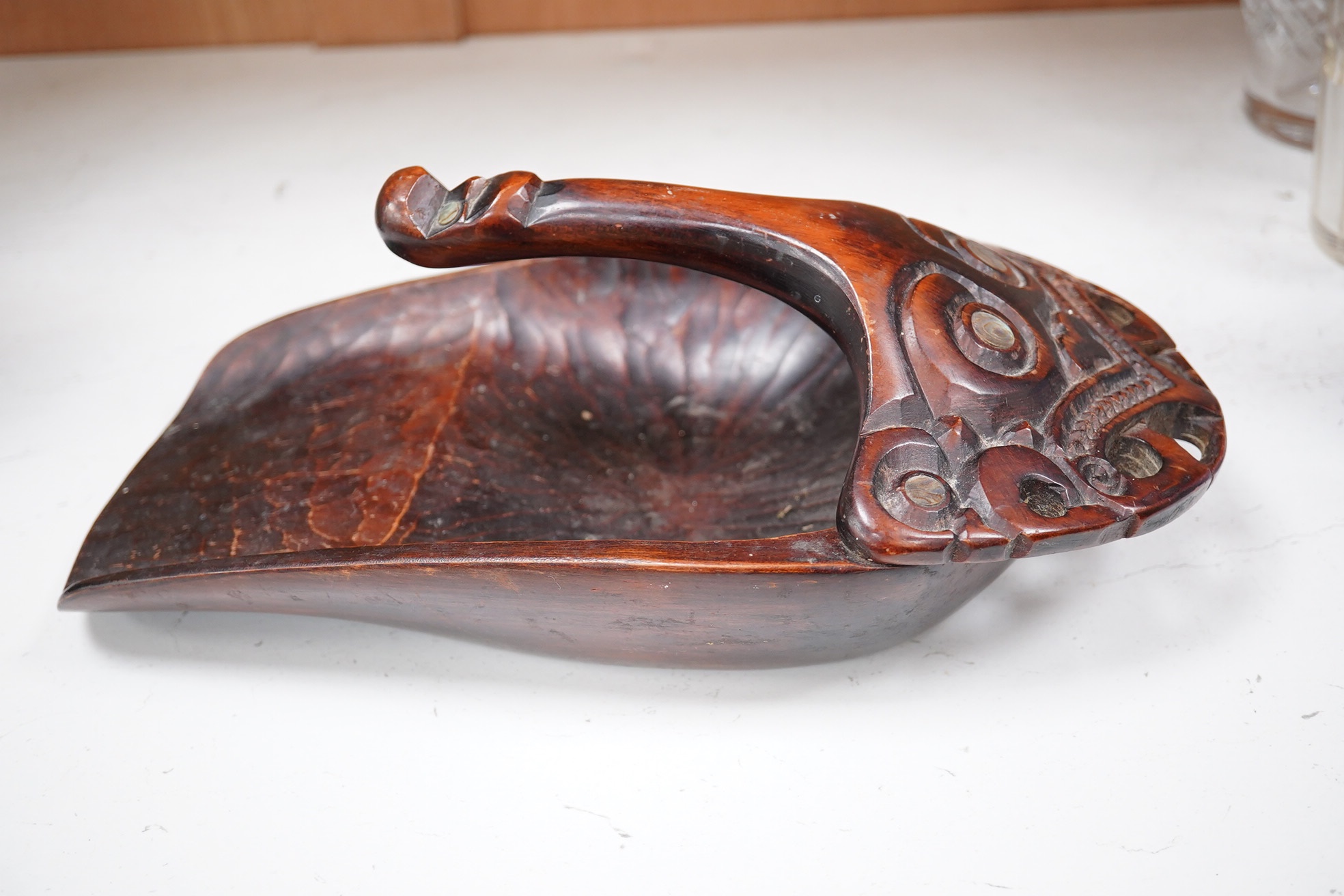 A carved Maori ta ta (water bailer) with mother of pearl inlay, 33cm long. Condition - good